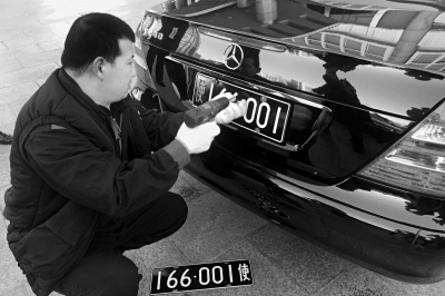 2月13日上午,在外交部院内,工作人员正卸下一辆外交车辆的旧版车牌